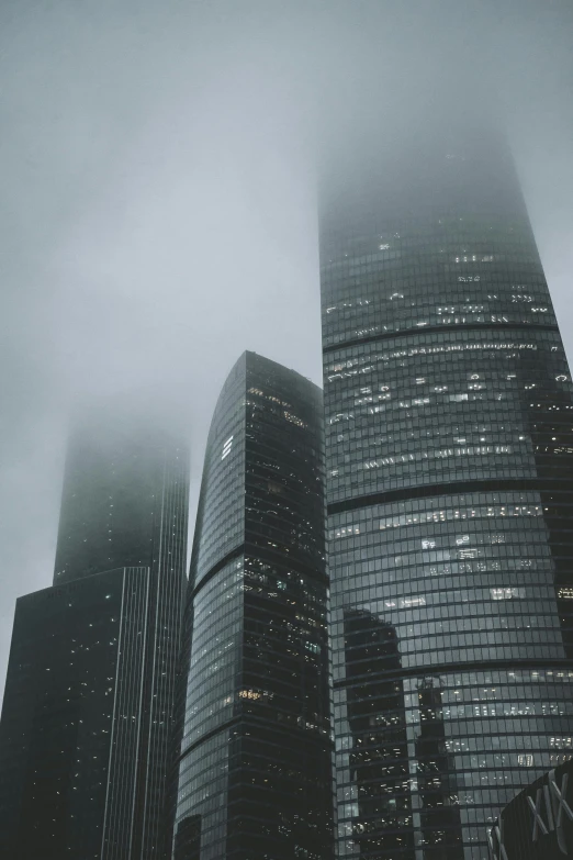 two very tall buildings with fog around them