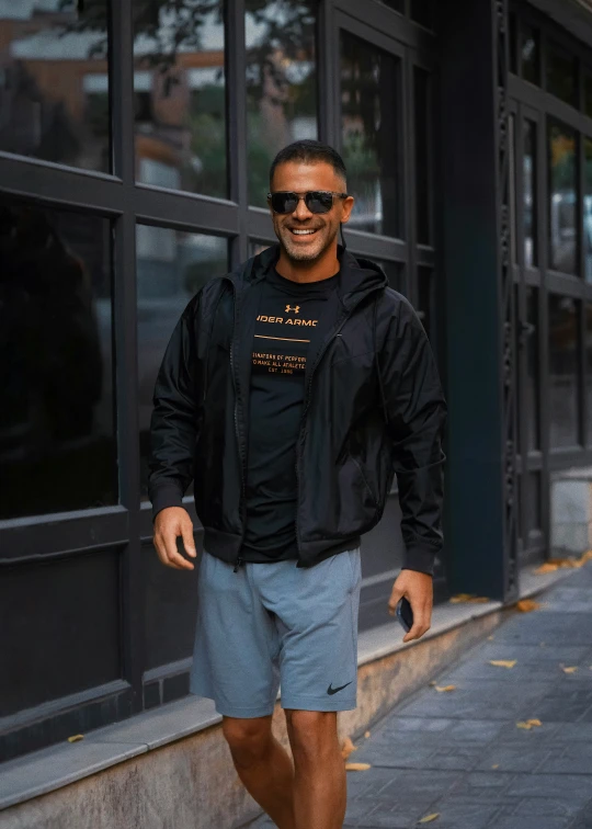 man in black jacket walking down sidewalk near building