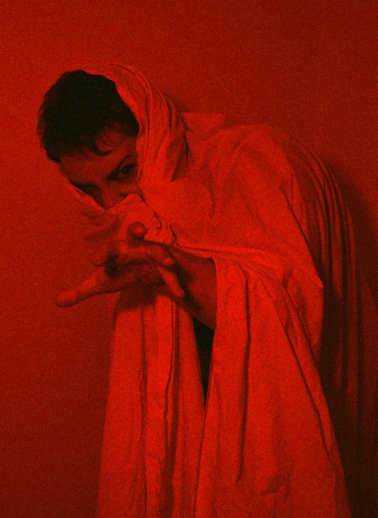 a man wrapped in a red cloth touching his wrist