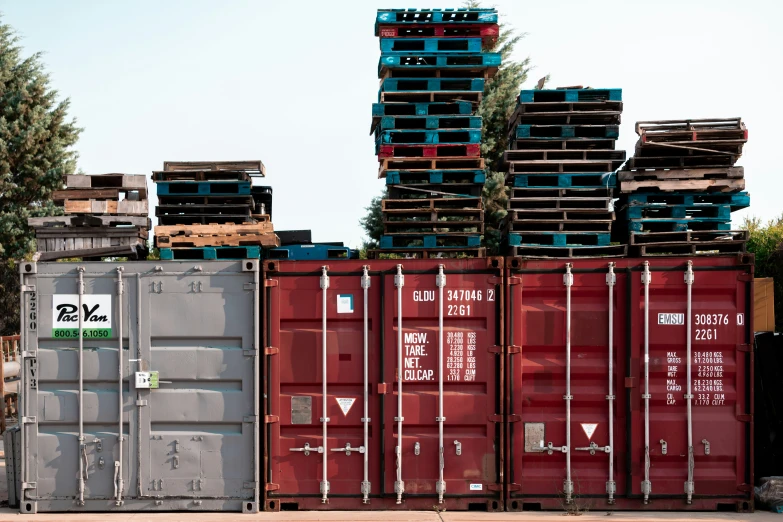 a bunch of containers are stacked up with some tree tops