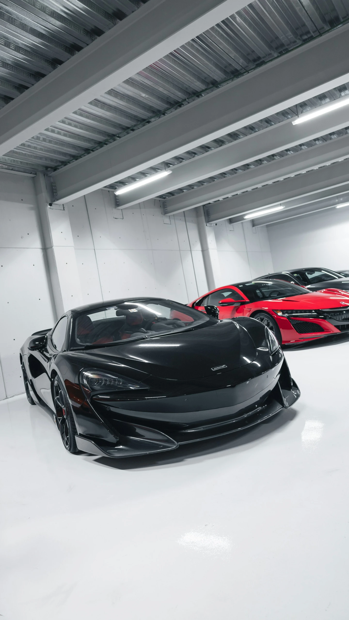 a black sports car in the garage with other red cars