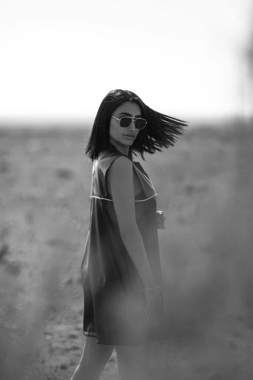 a young woman is standing in the sand in sunglasses