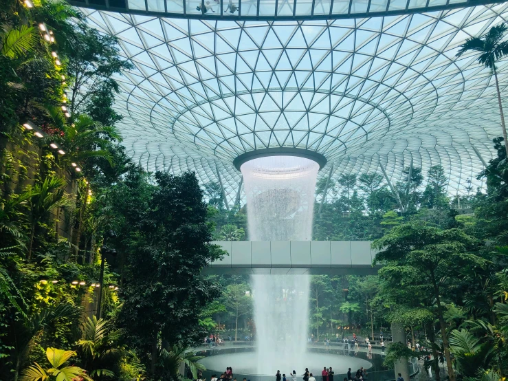 a waterfall in a garden with people walking by