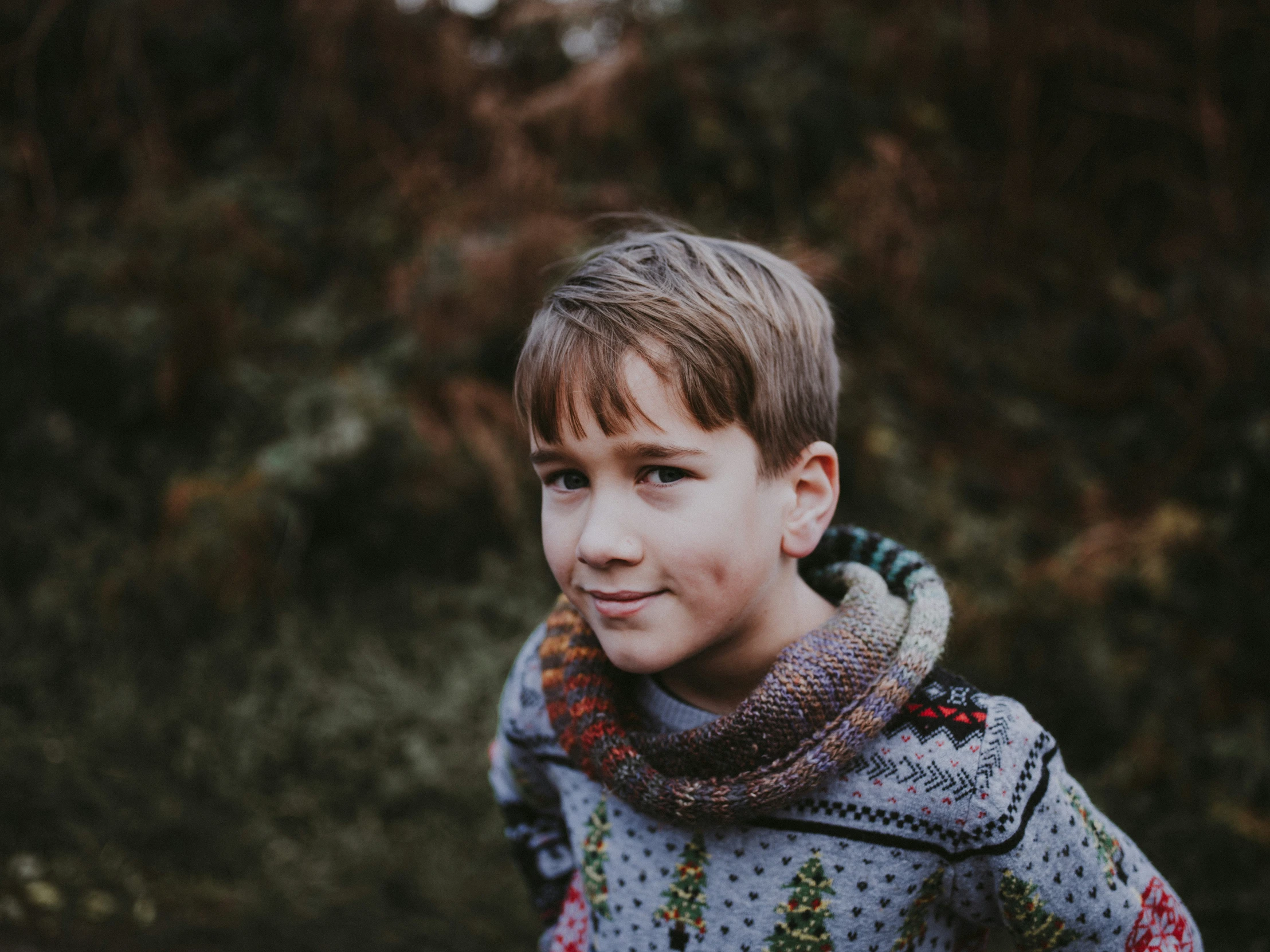 boy in a sweater looks at the camera and smiles