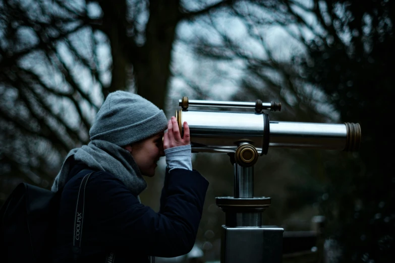 a person looking through a telescope into a forest