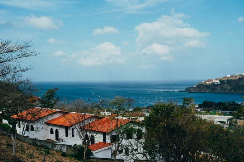 a white house sits on the hillside of a hill near the water