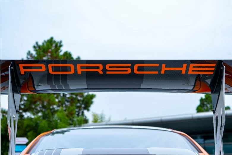 a parked orange porsche car with the word porsche on it