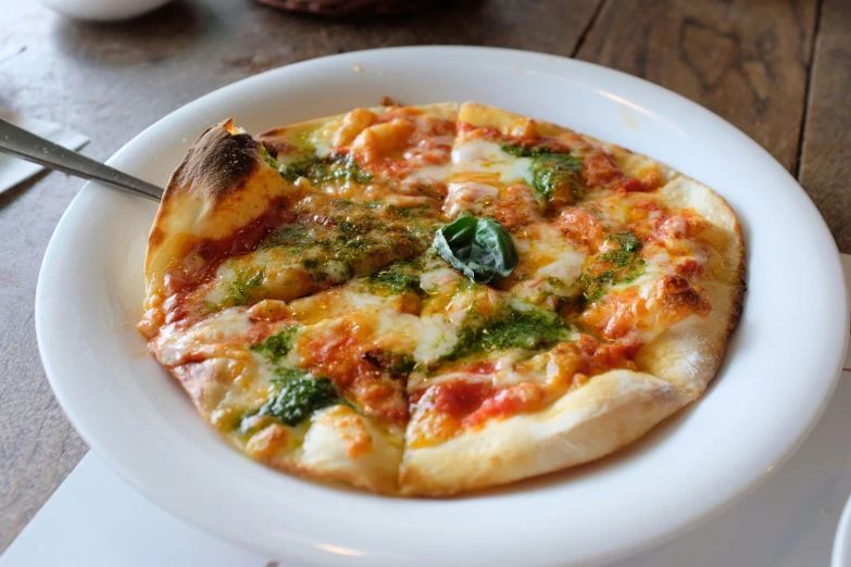 a small pizza on a plate is served on a white plate