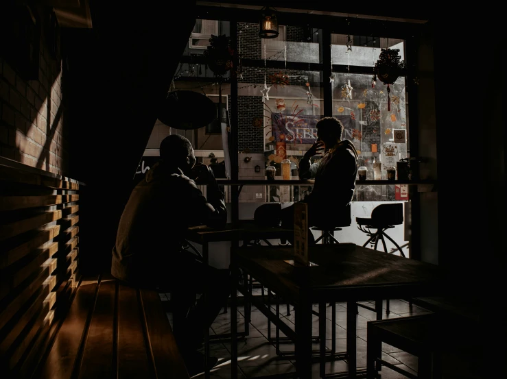 a person sitting at a wooden table in front of a window