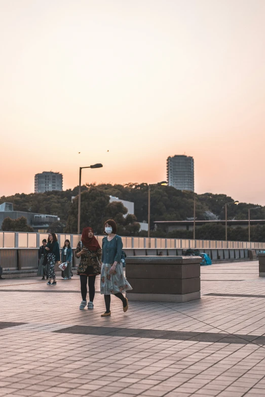 people in a city park at sunset with buildings in the background