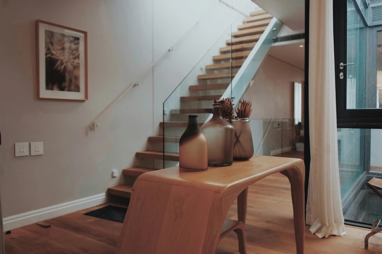 a table with vases and artwork in it next to stairs