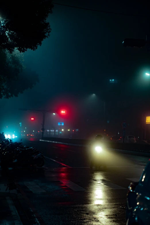 cars driving through an intersection at night with street lights