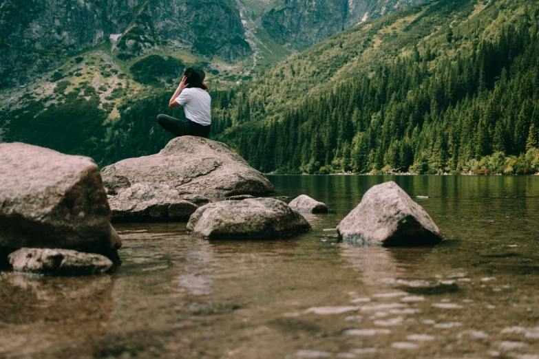 a woman sitting on rocks overlooking a body of water