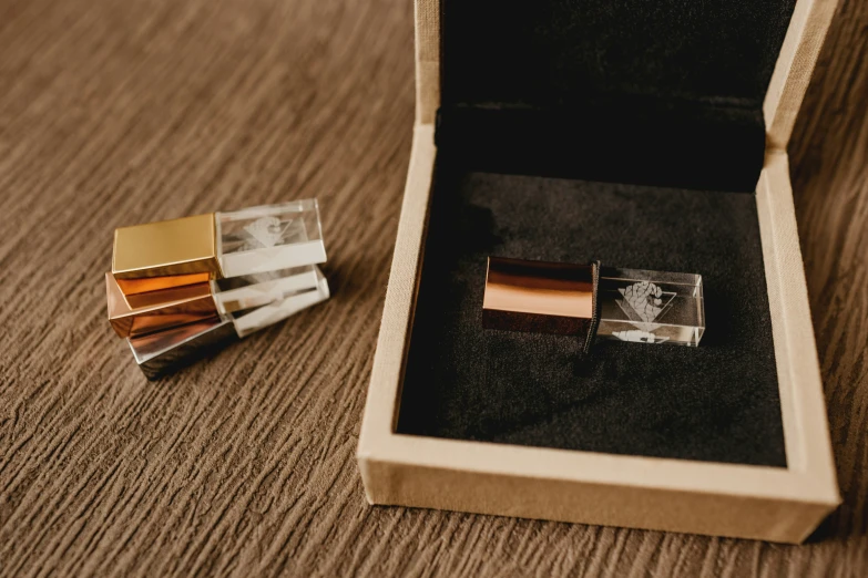 a box with two gold cufflinks inside and two different designs