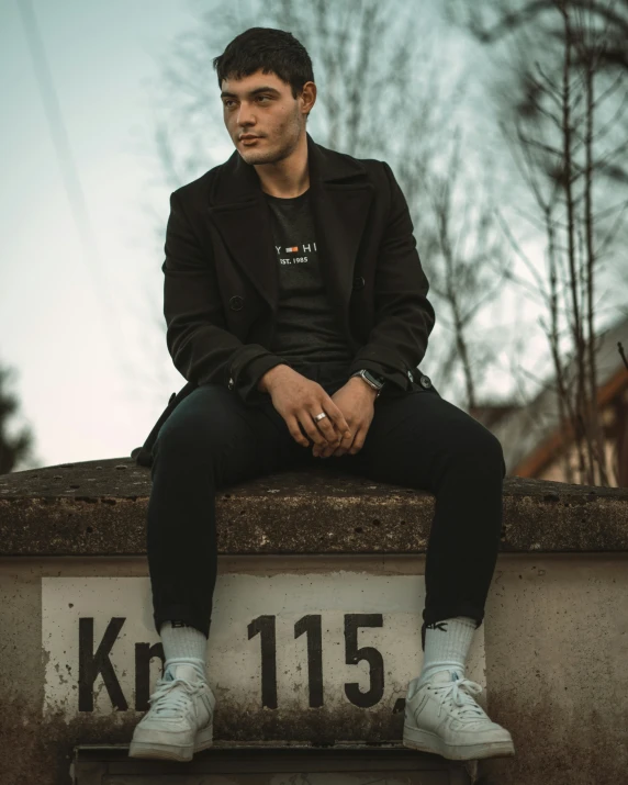 a man wearing black is sitting on the top of a building