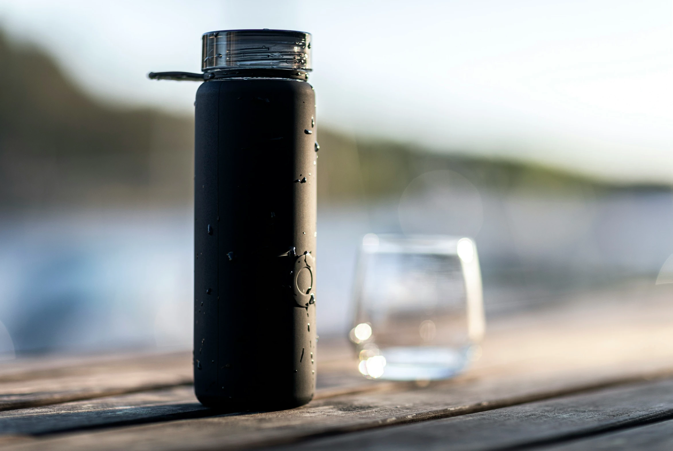 a bottle on a table next to a glass