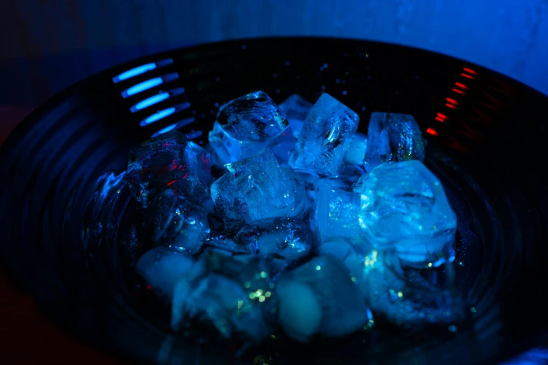 ice cubes in a black bowl that is on a table