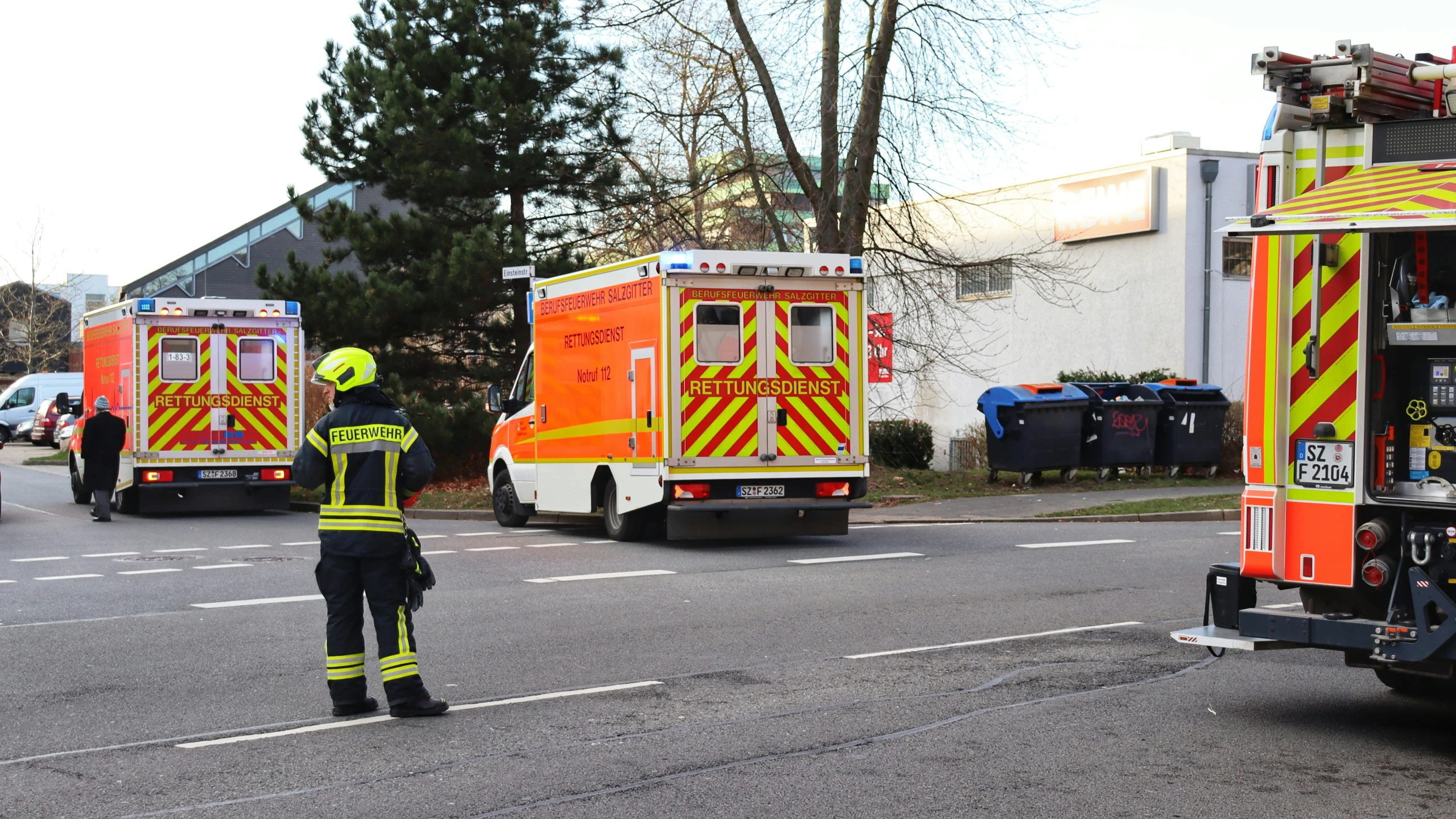 an ambulance crew standing near the side of a street next to some ambulance vehicles