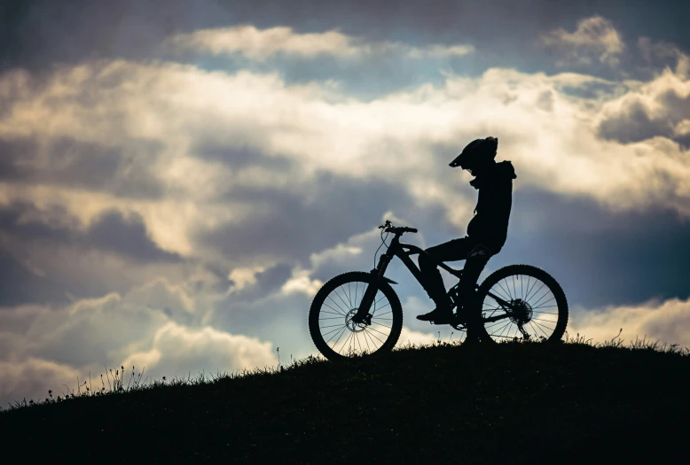 the silhouette of a bike rider on a steep incline