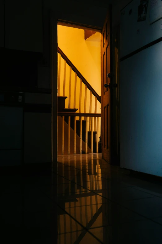 a door is opened to a hallway with stairs leading to the kitchen