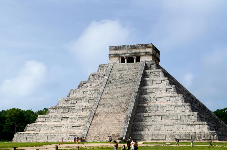 a group of tourists look up at the tall pyramid