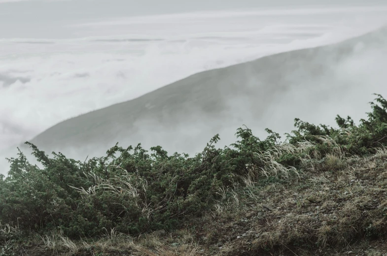 a foggy mountain is seen with some low clouds