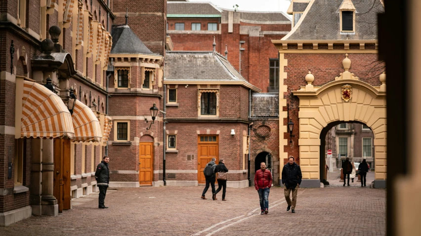 several people walking down a brick street near buildings