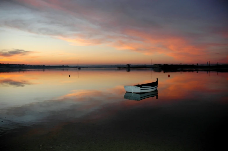 a small boat sits in the still water near a dock