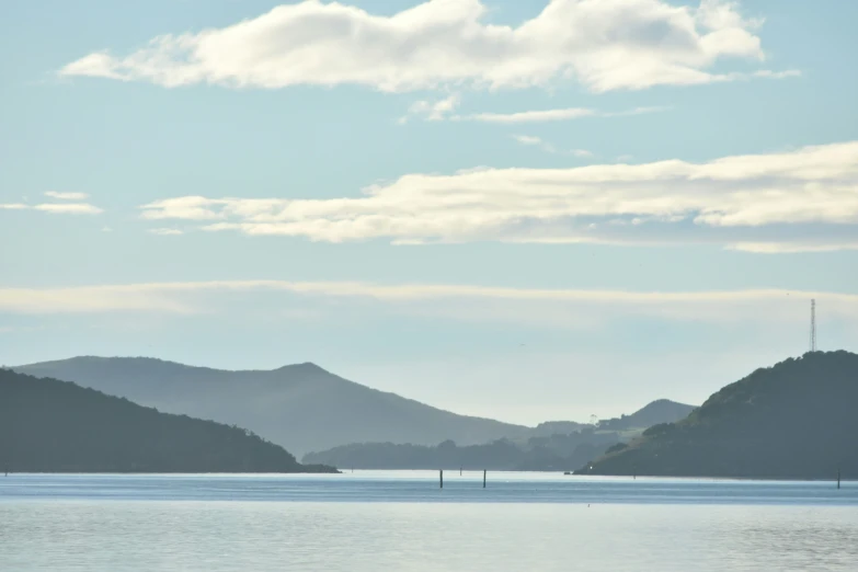 some hills are by the water and a couple boats