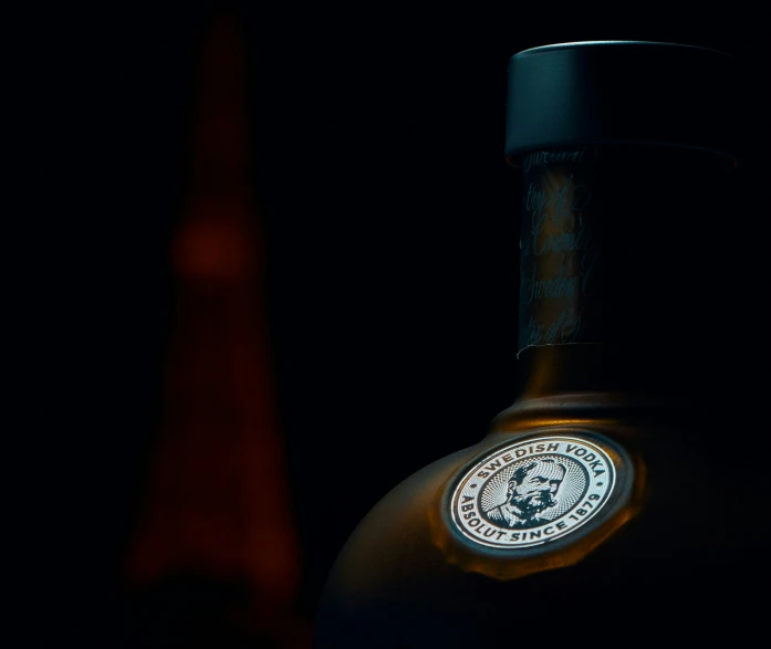 a bottle with a lion head on it sitting in the dark