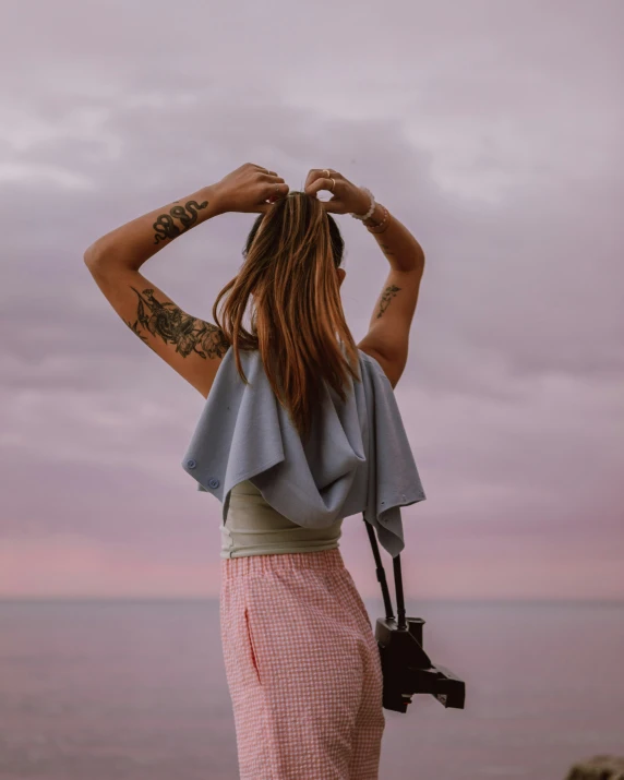 a woman that is standing near the ocean with a camera