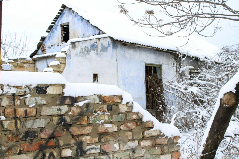 a house and wall covered in snow with no roof