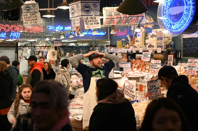 a man is pointing to soing with both hands in a crowded area