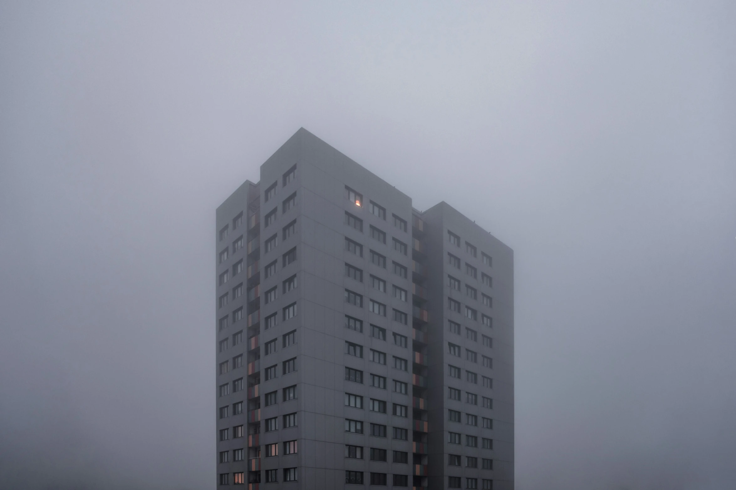 the tall building on a foggy day has lit lights