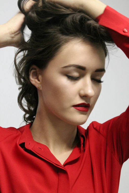 a woman in red shirt touching her hair with one hand