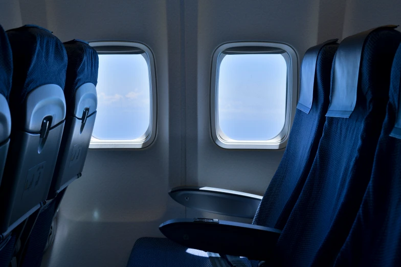 a plane with the windows open revealing the airplane seat and the windows are facing out