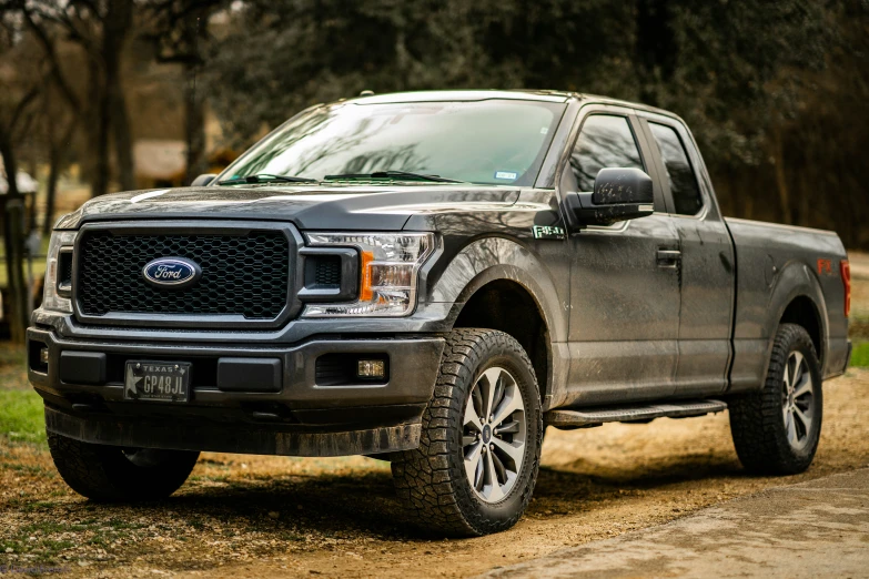 a black truck parked in dirt road with trees