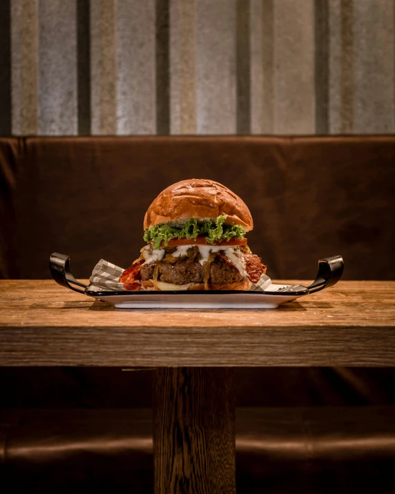 a large hamburger on a wooden table with a knife on it