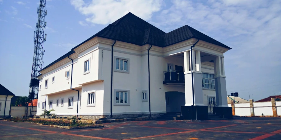 a white two story building next to a tall white fence