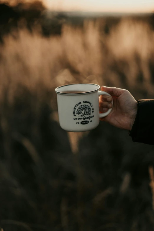 a person holding a white cup in their hand