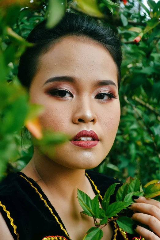 an asian lady with green leafy hair wearing an ethnic necklace