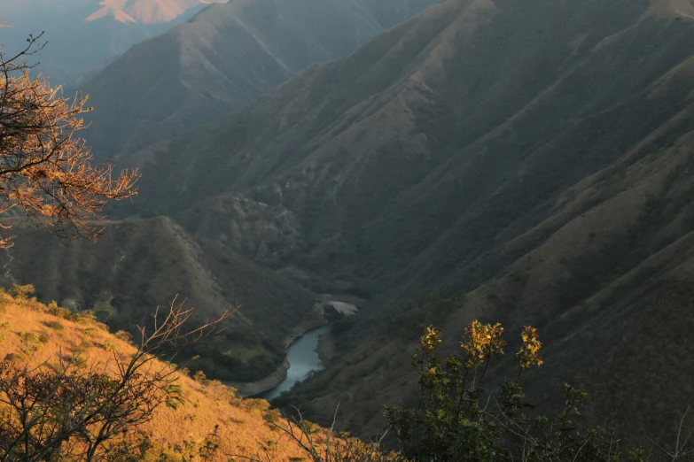 the mountains rise high above a stream in an area of brown