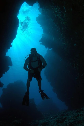 a scubas in the deep blue water of an underwater cave