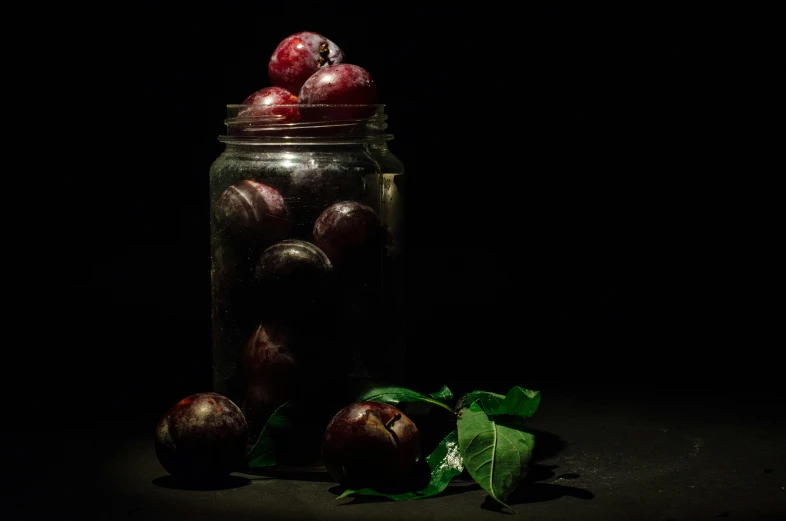 some apples and some leaves on a dark table