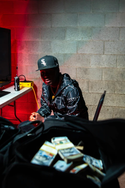 man sitting at a desk with stacks of money and laptop