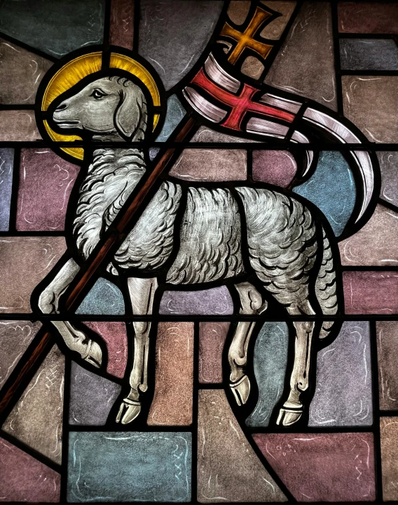 a stained glass window with a sheep holding a flag