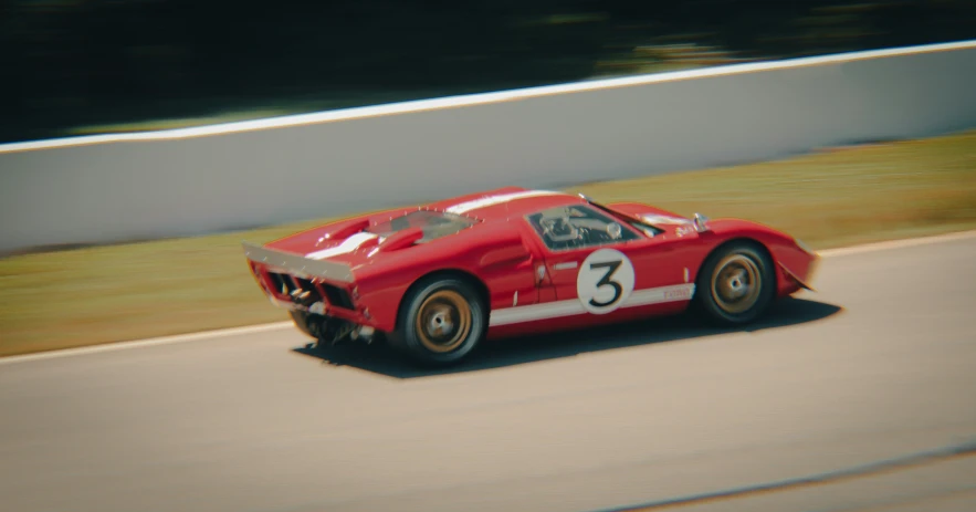 a red vintage racing car driving down the road