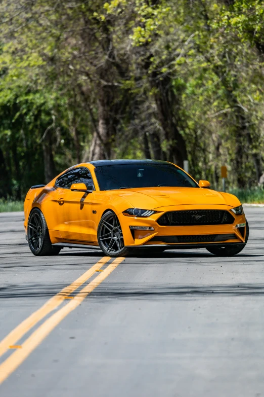 a yellow ford mustang is parked on the side of the road