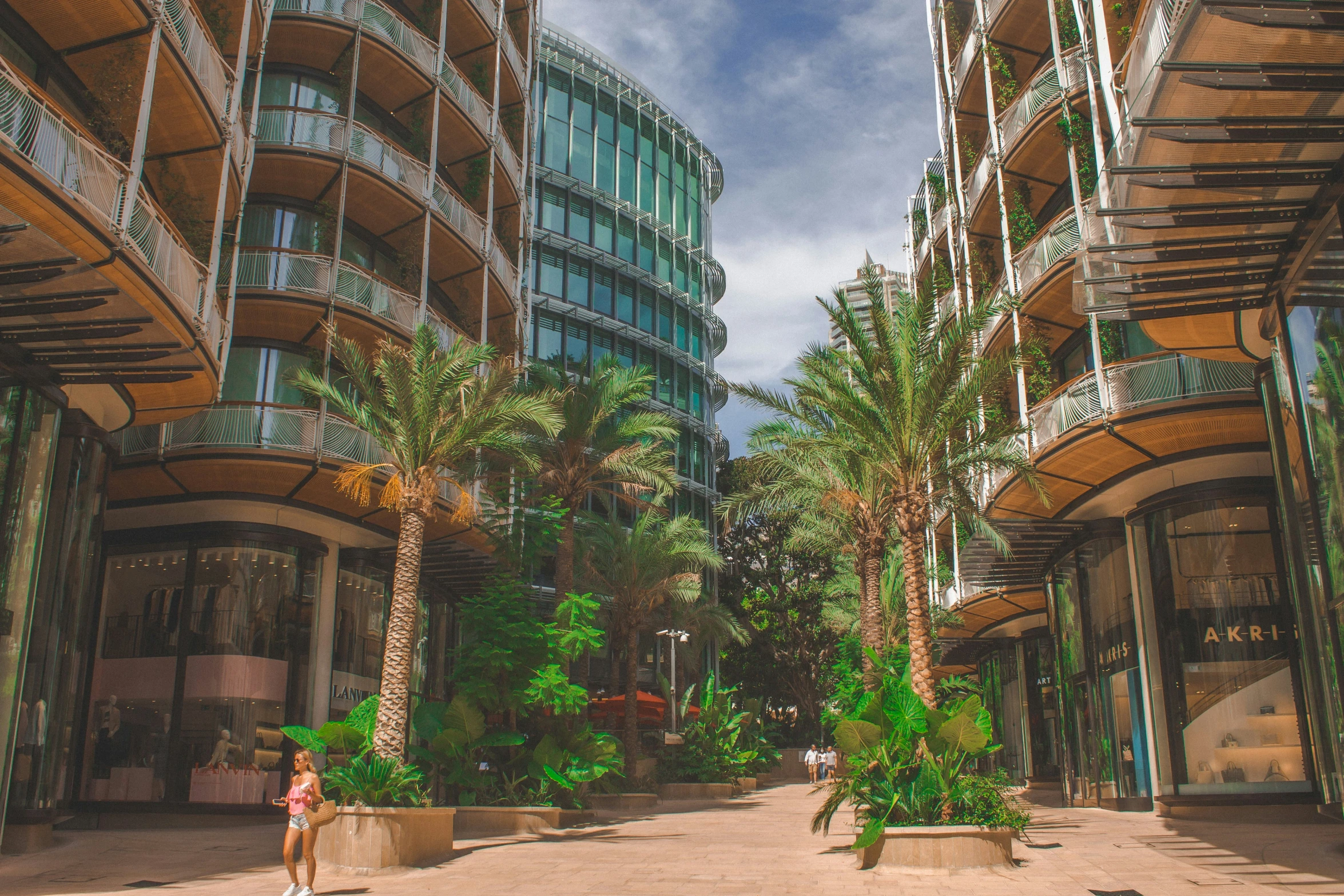 a woman walking through a lush green covered city square