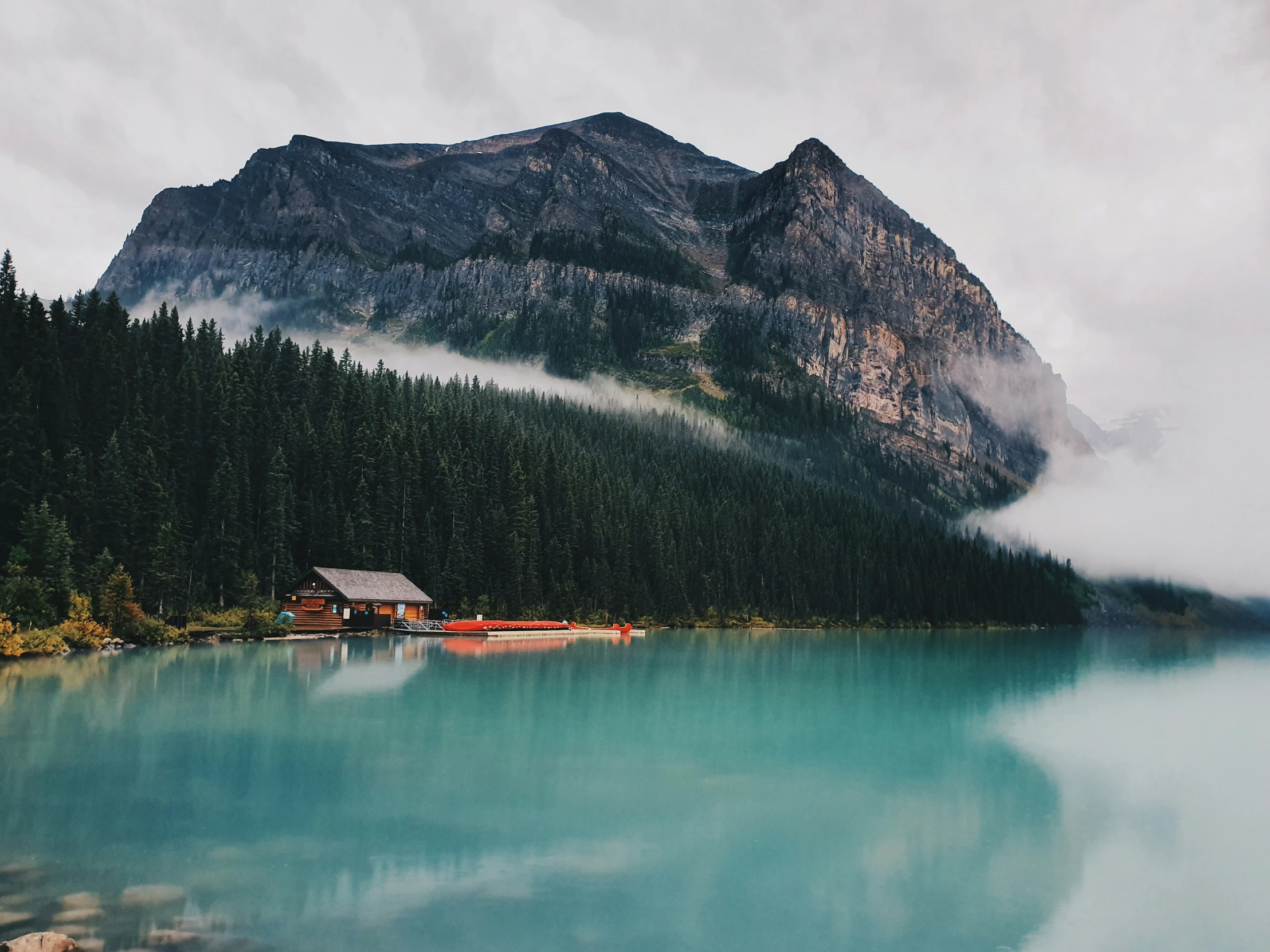 a lake with a hut on it near mountains